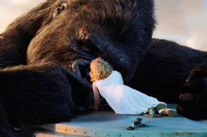 Blonde woman mouth kisses giant gorilla.